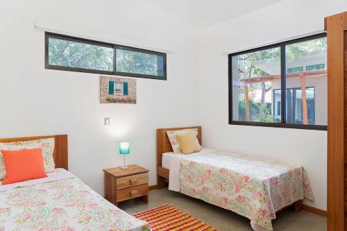 a bedroom with two beds and two windows at Eco Casita 11 in Rivas