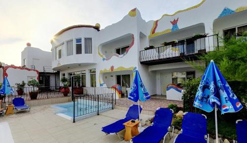 un patio con sillas azules y sombrillas frente a una casa en Hotel Laguna, en Vama Veche