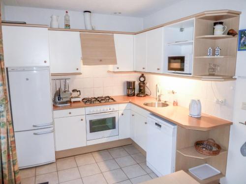 een kleine keuken met witte kasten en een wastafel bij Holiday Home Bosrijk Ruighenrode-3 by Interhome in Lochem