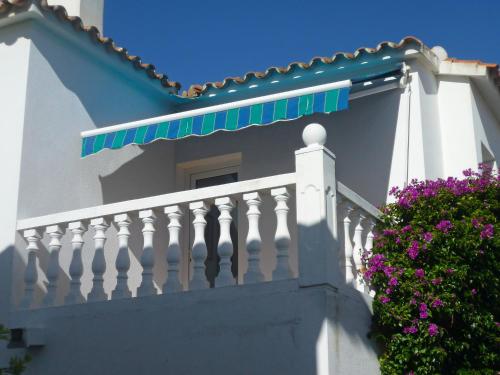 a white house with a balcony with purple flowers at Apartment Club Sevilla I by Interhome in Casas Devesa