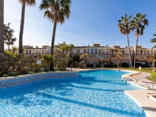 a swimming pool with palm trees and a building at Apartment La Rosaleda-3 by Interhome in Denia