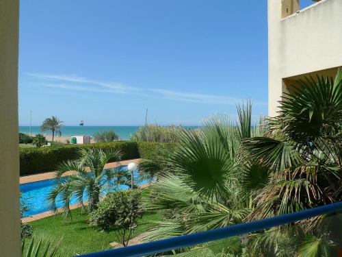 vistas a una piscina con palmeras y al océano en Apartment Las Dunas-3 by Interhome, en Denia