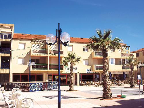 un éclairage de rue devant un bâtiment avec des palmiers dans l'établissement Lagrange Vacances Les Résidences, à Sainte-Marie-Plage