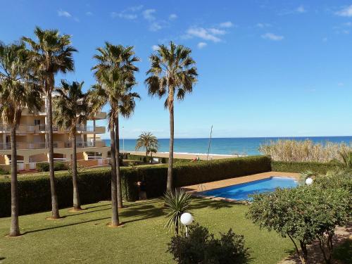 un complejo con piscina, palmeras y playa en Apartment Las Dunas-4 by Interhome, en Denia