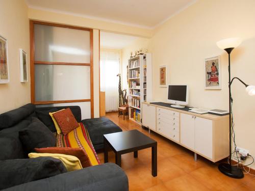 ein Wohnzimmer mit einem Sofa und einem Schreibtisch mit einem TV in der Unterkunft Apartment Sardenya - Casp by Interhome in Barcelona