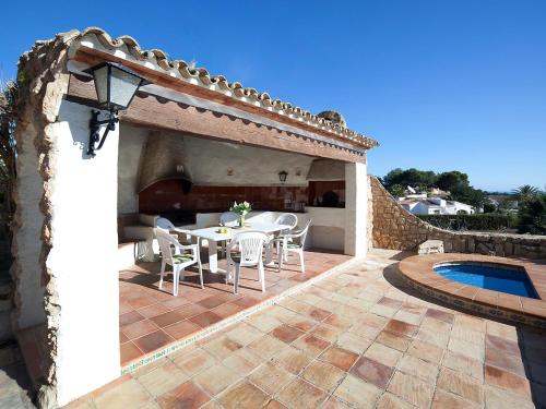 patio ze stołem i krzesłami oraz basenem w obiekcie Holiday Home Els Pins by Interhome w mieście Benissa
