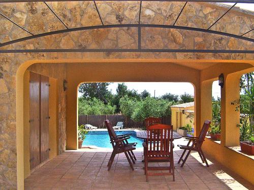 a patio with chairs and a table and a pool at Holiday Home Ulldellops by Interhome in L'Ampolla