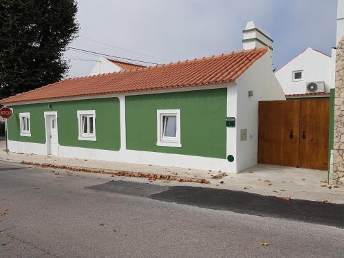 a small green and white building with a gate at Casas do Patheo in Óbidos