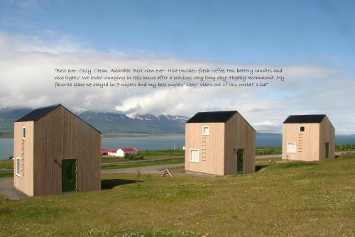 a group of three buildings on top of a field at Sunnuhlid houses in Akureyri