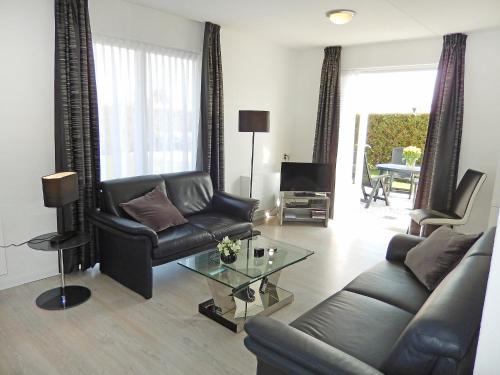 a living room with a leather couch and a table at Holiday Home de Witte Raaf-1 by Interhome in Noordwijk