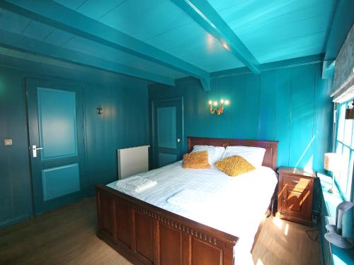 エンクホイゼンにあるVilla VOC-Huys by Interhomeの青い壁のベッドルーム1室、黄色い枕付きのベッド1台が備わります。