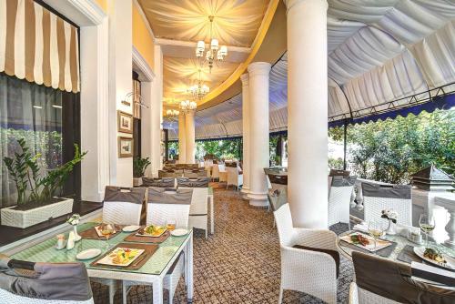 un restaurante con mesas blancas, sillas y columnas en Oreanda Premier Hotel, en Yalta