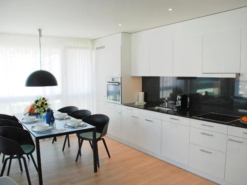 a kitchen with white cabinets and a table and chairs at Apartment LaVille B-3-2 by Interhome in Locarno