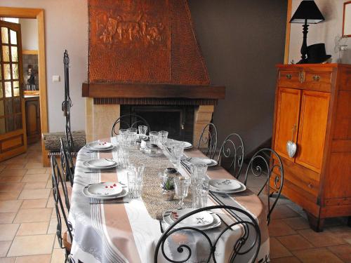 a table with glasses and plates on it with a fireplace at Holiday Home La Ferme de Gabrielle by Interhome in Le Bizet