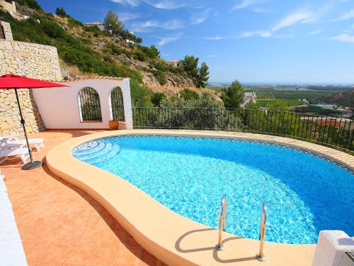 a swimming pool with an umbrella next to a house at Holiday Home Del Azahar by Interhome in Monte Pego