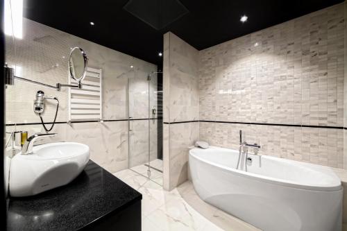 a bathroom with a white tub and a sink and a mirror at Słoneczny Zdrój Medical Spa & Wellness in Busko-Zdrój