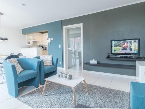 a living room with a blue couch and a tv at Apartment Residentie Duinenbries-1 by Interhome in Bredene