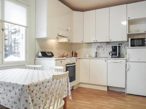 uma cozinha com armários brancos e uma mesa com cadeiras em Holiday Home Levin mummola by Interhome em Köngäs