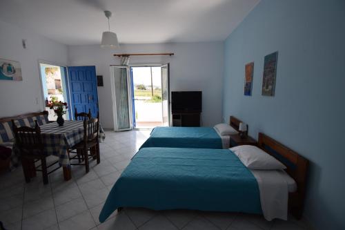 a bedroom with two beds and a dining room with a table at Palmos Self-Catering Apartment in Kastraki Naxou