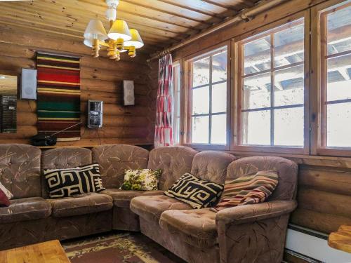 uma sala de estar com um sofá castanho e janelas em Holiday Home Karhuntuuli by Interhome em Luosto