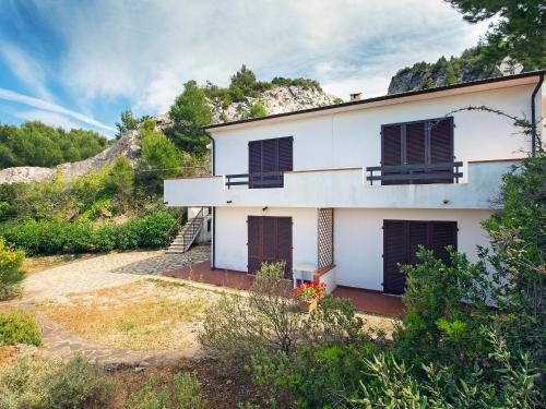 una casa bianca con porte marroni e una collina di Apartment la Roccia by Interhome a Cavo
