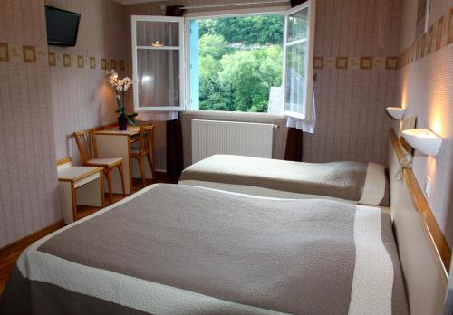 a hotel room with two beds and a window at Hotel Restaurant des Deux Vallées in Entraygues-sur-Truyère