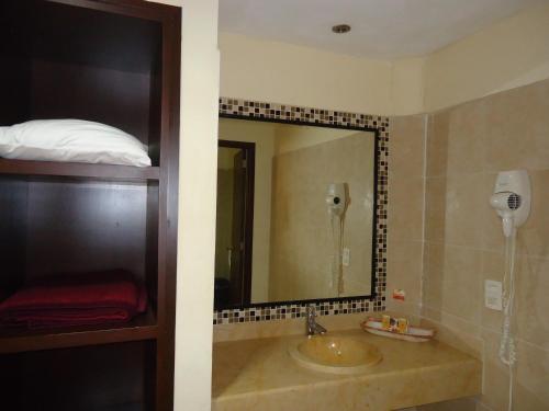 ein Badezimmer mit einem Waschbecken und einem großen Spiegel in der Unterkunft Hotel Plaza San Carlos in Xicotepec de Juárez