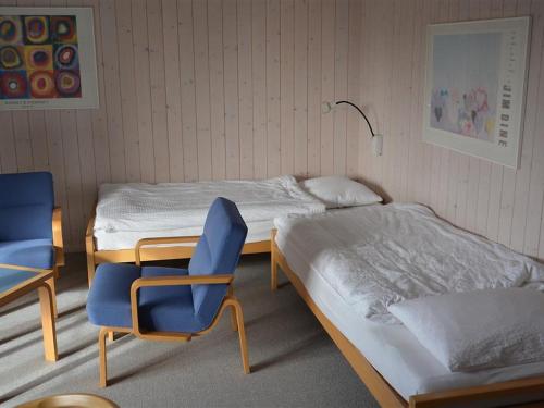 グスタードにあるApartment Arlette Nr- 30 by Interhomeのベッド2台と青い椅子2脚が備わる客室です。