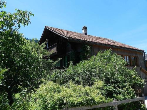 een houten huis met bomen ervoor bij Apartment Im Wiesengrund by Interhome in Gstaad