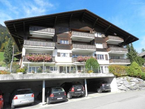 a large building with cars parked in front of it at Apartment Fink by Interhome in Zweisimmen