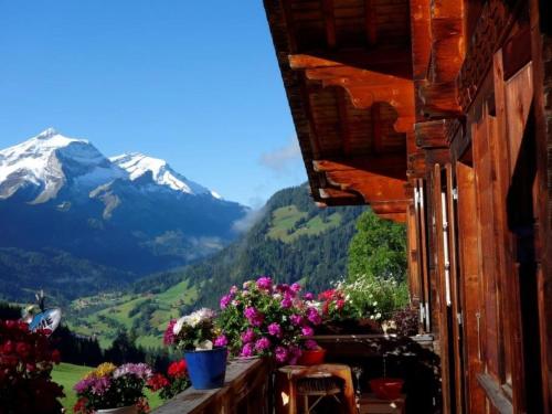 een balkon met bloemen en uitzicht op een berg bij Apartment Am Bächli by Interhome in Gsteig