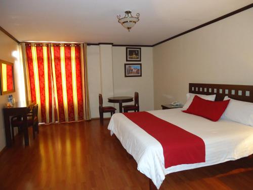 a bedroom with a large bed with a red and white blanket at Hotel Plaza San Carlos in Xicotepec de Juárez