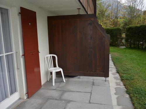 a white chair sitting in front of a door at Apartment Oberland Nr- 29 by Interhome in Gstaad