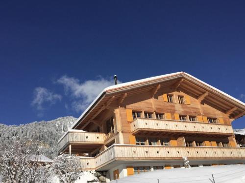 a large wooden building with snow on the ground at Apartment Butterfly by Interhome in Adelboden