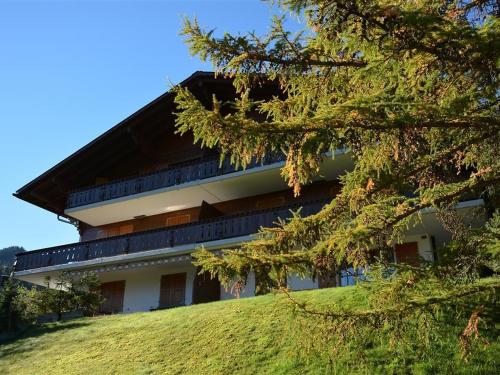 un bâtiment au sommet d'une colline avec un arbre dans l'établissement Apartment Hornflue - Wohlwender by Interhome, à Gstaad