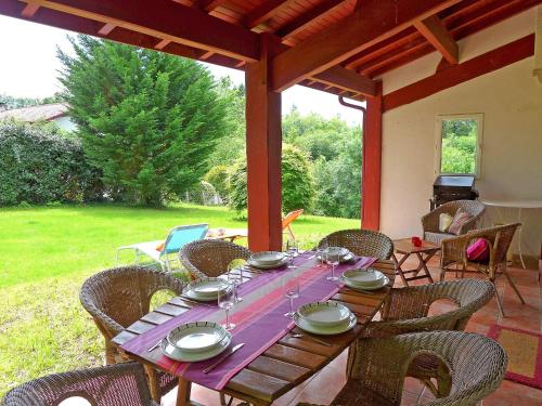 - une table en bois avec des assiettes et des verres à vin sur la terrasse dans l'établissement Holiday Home Eki Alde by Interhome, à Saint-Pée-sur-Nivelle