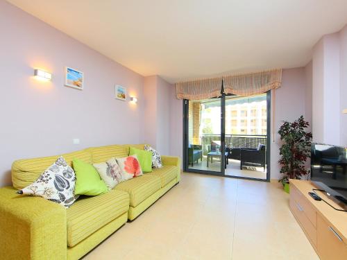 a living room with a yellow couch with pillows at Apartment Can Pavet by Interhome in Vilafortuny
