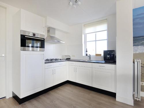 a white kitchen with white cabinets and a window at Holiday Home Tapuit 8-2 by Interhome in Noordwijk