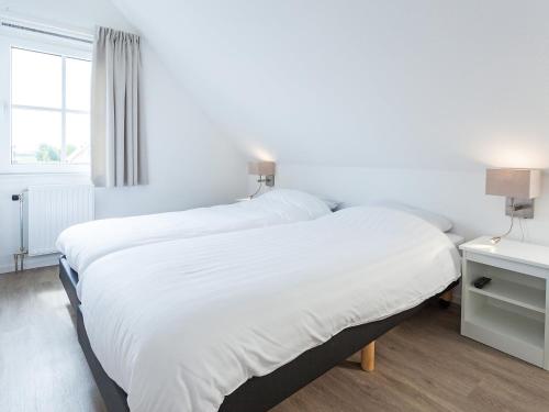a bedroom with two beds with white sheets and a window at Holiday Home Alk 6 by Interhome in Noordwijk