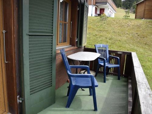 2 blaue Stühle und ein Tisch auf der Veranda in der Unterkunft Apartment Brandegg 4 by Interhome in Lenk im Simmental