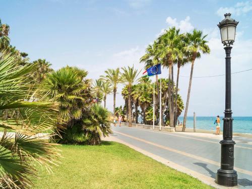 een straat met palmbomen en een straatlicht en de oceaan bij Apartment Las Adelfas by Interhome in Marbella