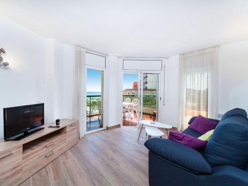 uma sala de estar com um sofá azul e uma televisão em Apartment Fanals-6 by Interhome em Platja d'Aro