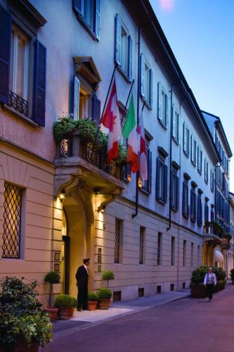 a man standing outside of a building with flags on it at Four Seasons Hotel Milano in Milan