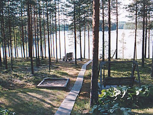 un camino en un parque junto a un lago con un banco en Holiday Home Aittoniemi i by Interhome, en Hopsu