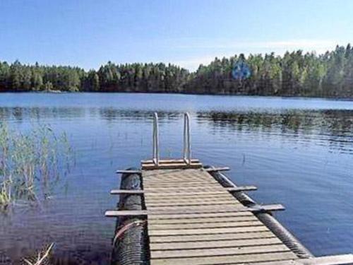 a wooden dock on a large lake with trees at Holiday Home Pikku-villa by Interhome in Vähäsalmi