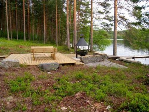 a wooden picnic table next to a lake with a lamp at Holiday Home 6309 by Interhome in Konginkangas