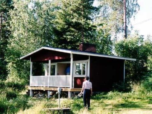 un homme debout devant une petite maison dans l'établissement Holiday Home Anna tuisku by Interhome, à Sorrinmäki