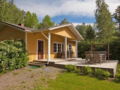 a small yellow house with a porch and a patio at Holiday Home Keltavuokko by Interhome in Sipsiö