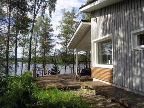 a house with a deck next to a body of water at Holiday Home Harjunniemi by Interhome in Vilppula