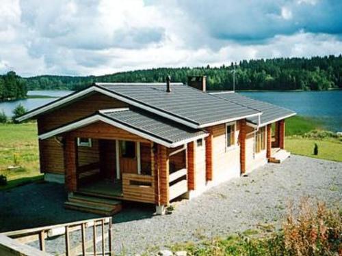 ein kleines Haus mit einem See im Hintergrund in der Unterkunft Holiday Home Petäjäinen by Interhome in Sipsiö